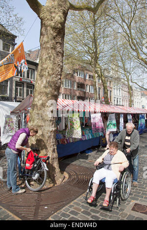 man pushes woman in wheelchair on market in the dutch town of breda Stock Photo