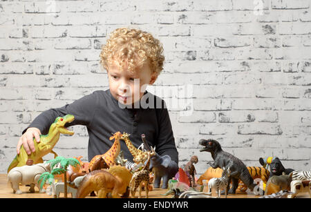 a little child plays with toys animals and dinosaur Stock Photo