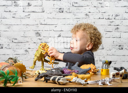 a little child plays with toys animals and dinosaur Stock Photo