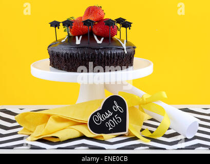 Happy Graduation Day yellow, black and white theme party with chocolate cake and strawberries. Stock Photo