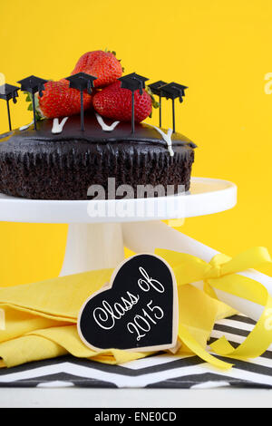 Happy Graduation Day yellow, black and white theme party with chocolate cake and strawberries. Stock Photo