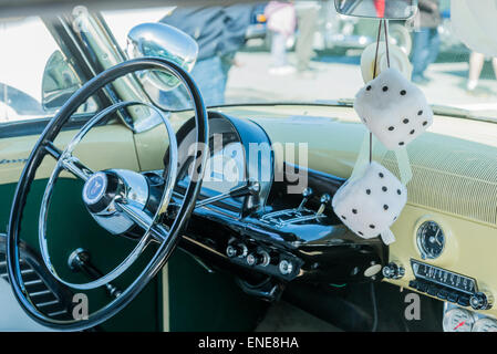 Fuzzy dice hanging from rear view mirror of classic automobile. Stock Photo