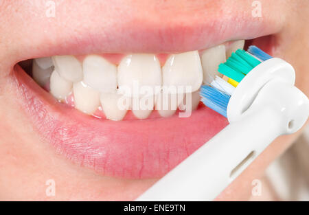 Woman brushing teeth with electric toothbrush, closeup Stock Photo