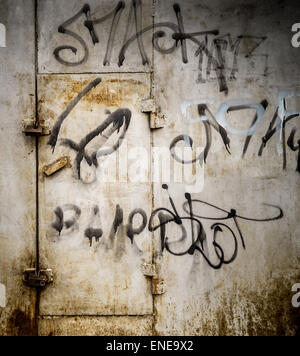 City street paint in black on Grey rusted metal with a locked door in rust Stock Photo