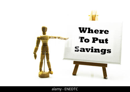 Wooden man with white board pointing at words 'where to put savings' save for future pension old age investment invest Stock Photo
