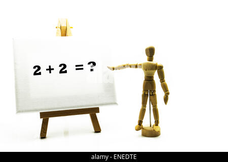 Wooden man with white board pointing at words '2 + 2 = ?' sum sums education educational concept math maths arithmetic school Stock Photo