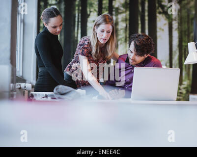 Young female executive presenting her ideas to colleagues in a meeting. Young people discussing work at desk in office. Stock Photo