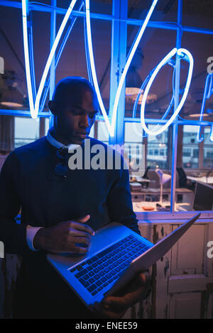 Young man in office working on laptop. African business executive standing with a laptop computer. Stock Photo