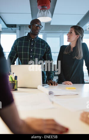 Business people discussing ideas during a meeting around a table in office. Diverse team of young professionals working on new b Stock Photo