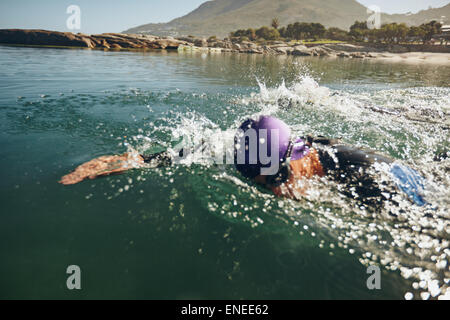 Male competitor swims freestyle in the water. Male athlete swimming on a triathletic competition. Stock Photo