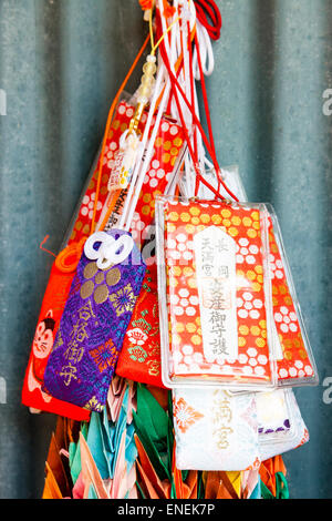 Several tiny drawstring like little bags, omamori, hanging at a Japanese shrine. The design of these protective charms is from the Heian era. Stock Photo