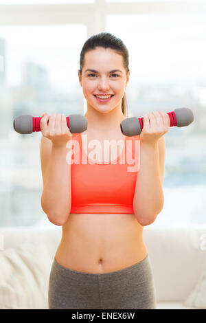 smiling teenage girl exercising with dumbbells Stock Photo