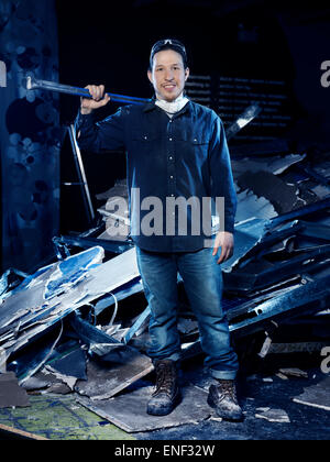 Portrait of a man, construction worker, with a sledgehammer standing by a pile of rubble from demolition Stock Photo