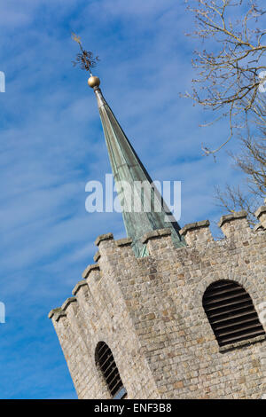 Traditional English church tower, topped with a metal clad spire and weather vane, taken at a jaunty angle. Stock Photo