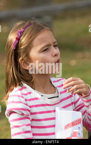 Young girl eating popcorn from a paper bag Stock Photo
