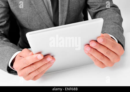 closeup of a young caucasian businessman in gray suit sitting at his office desk uses a tablet computer Stock Photo