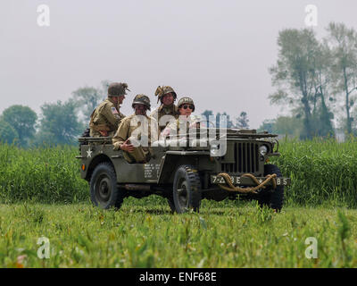 American US Allied Soldiers in WW2 Uniform seated in a Willys Jeep in a meadow as part of the D-Day Anniversary, Normandy France Stock Photo