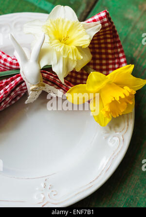 Spring festive easter dining table setting with yellow daffodil flowers,  napkins and vintage cutlery on a wooden board Stock Photo