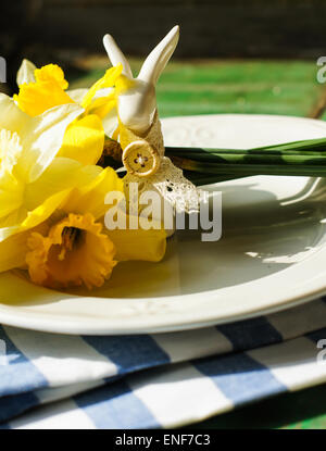 Spring festive easter dining table setting with yellow daffodil flowers,  napkins and vintage cutlery on a wooden board Stock Photo