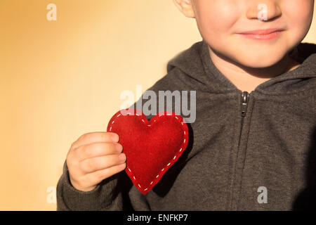 Red heart in child hands. Kindness concept, gift, hand made valentine, close up, horizontal, copy space Stock Photo