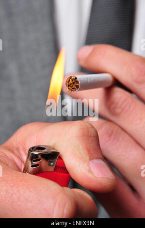 a man wearing a suit lighting a cigarette with a lighter Stock Photo