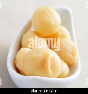 closeup of a bowl with macadamia nuts on a set table with beige tablecloth Stock Photo