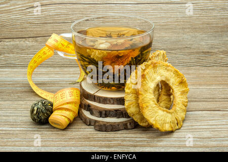 Dietary jasmine tea and dried pineapple on a wooden background. Stock Photo