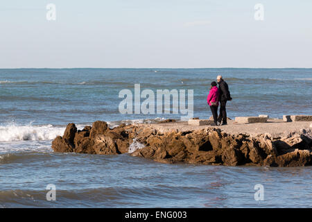 elderly couple enjoy the view on seacoast in winter, sea contemplation Stock Photo