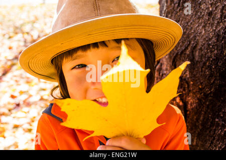 Close up of smiling mixed race boy holding autumn leaf