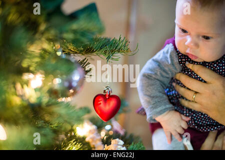 Caucasian parent holding baby girl near Christmas tree Stock Photo