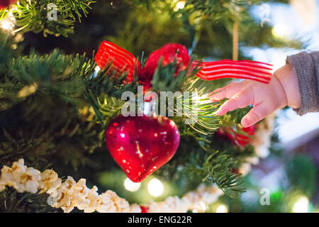 Close up of hand of Caucasian baby girl near Christmas tree Stock Photo