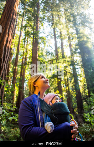 Low angle view of Caucasian mother carrying daughter in forest Stock Photo