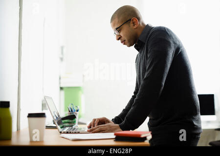 Mixed race businessman working on laptop at desk Stock Photo