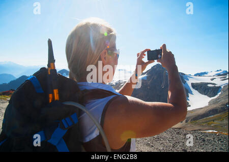 Woman taking photograph of remote mountains Stock Photo