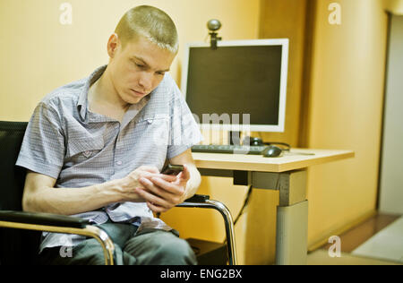 Caucasian man using cell phone at computer desk Stock Photo