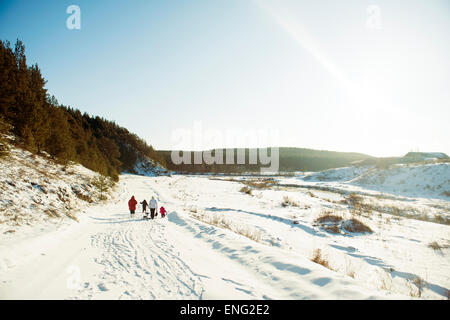 Caucasian family cross-country skiing in snowy field Stock Photo