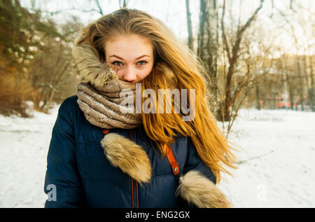 Caucasian woman wearing fur hood and coat in snowy field Stock Photo