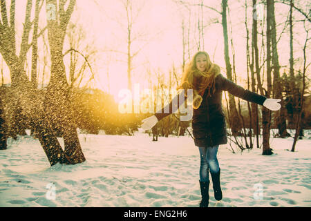 Caucasian woman playing in snowy field Stock Photo