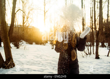 Caucasian woman playing in snowy field Stock Photo