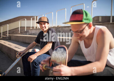 Caucasian men with skateboards sitting on steps Stock Photo