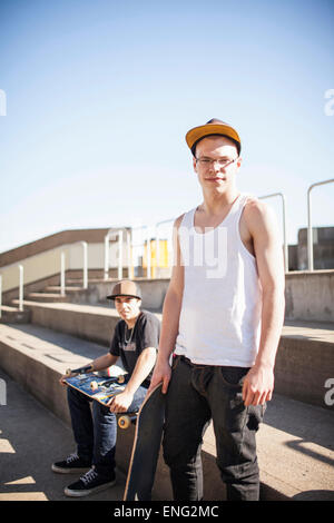 Caucasian men with skateboards sitting on steps Stock Photo