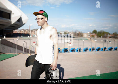 Caucasian man carrying skateboard near stadium Stock Photo