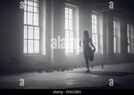 Black woman stretching in dark gym Stock Photo