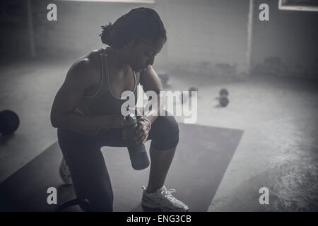 https://l450v.alamy.com/450v/eng3cb/black-woman-drinking-water-bottle-in-dark-gym-eng3cb.jpg