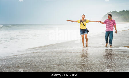 Hispanic couple playing in waves on beach Stock Photo