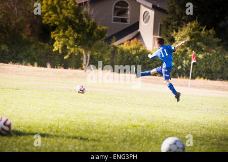 Mixed race boy playing soccer on field Stock Photo