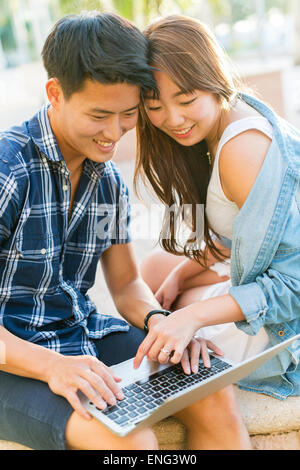 Korean couple using laptop outdoors Stock Photo