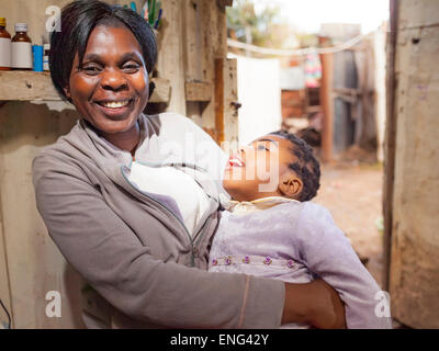 Close up of smiling black mother holding daughter in hut Stock Photo