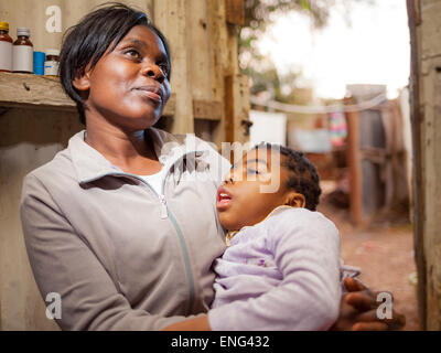 Close up of smiling black mother holding daughter in hut Stock Photo