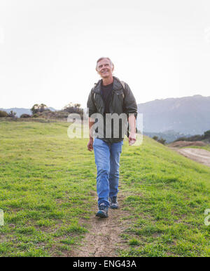 Older Caucasian man walking on dirt trail Stock Photo